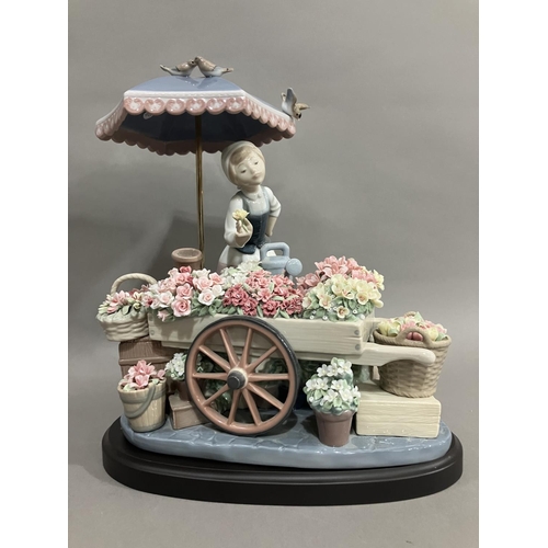 46 - A Lladro figure group, Flowers of the Season, of a girl with flower cart under an umbrella, 30cm hig... 