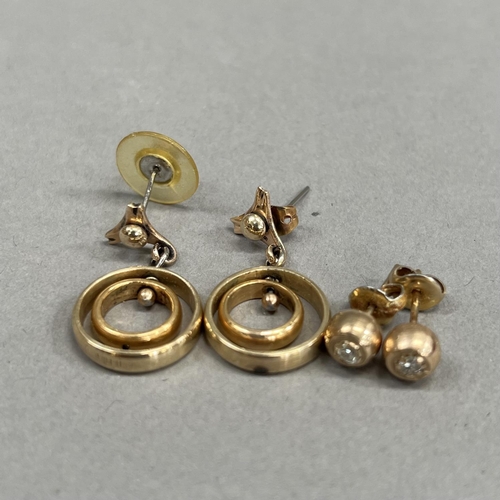 451 - A pair of ear pendants each of concentric yellow metal rings (tests as gold) hung on base metal post... 