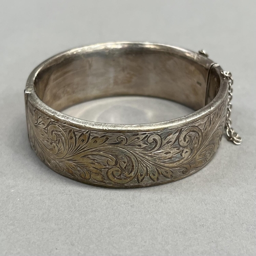 461 - A stiff hinged bangle in silver, circa 1958, half foliate scroll engraved, approximate width 22mm, a... 