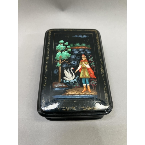 38 - A Russian black lacquered trinket box, rectangular, the cover painted with a figure and swan, 8.5cm ... 