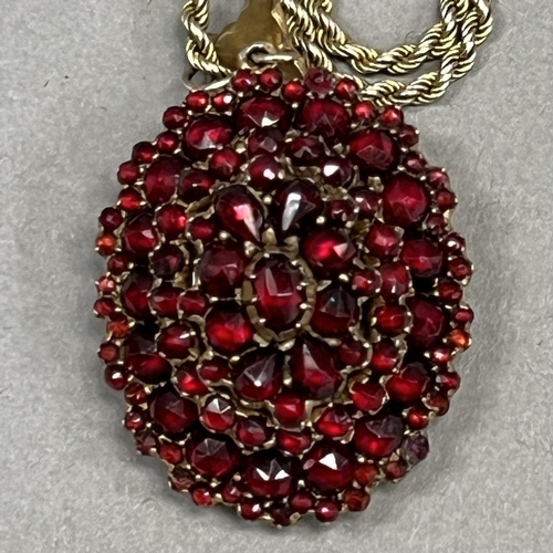 446 - A 19th century Bohemian garnet cluster pendant/locket of oval outline all over set to the front and ... 