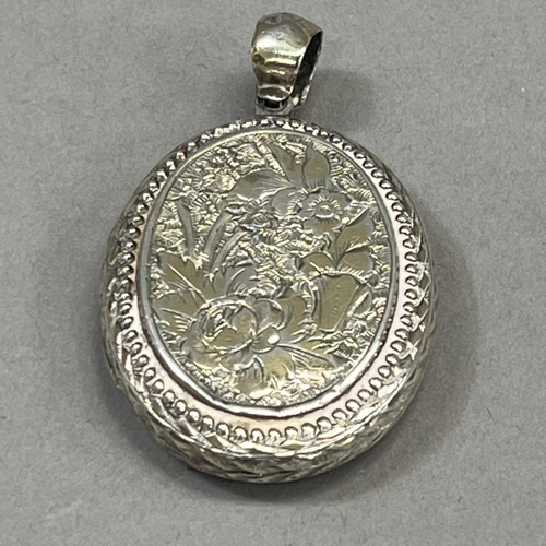 441 - A Victorian oval silver locket foliate engraved to the front with an open shield cartouche and folia... 