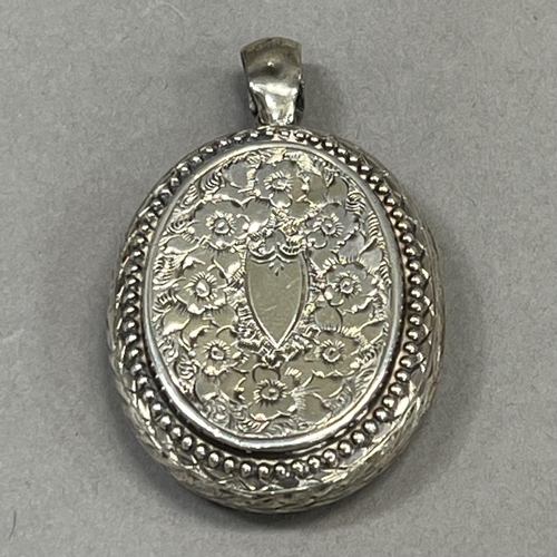 441 - A Victorian oval silver locket foliate engraved to the front with an open shield cartouche and folia... 