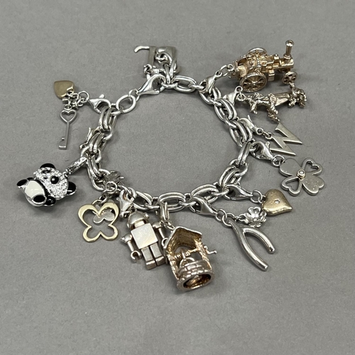 425 - A silver bracelet of trace and jump ring links hung with silver charms variously set with enamel, co... 