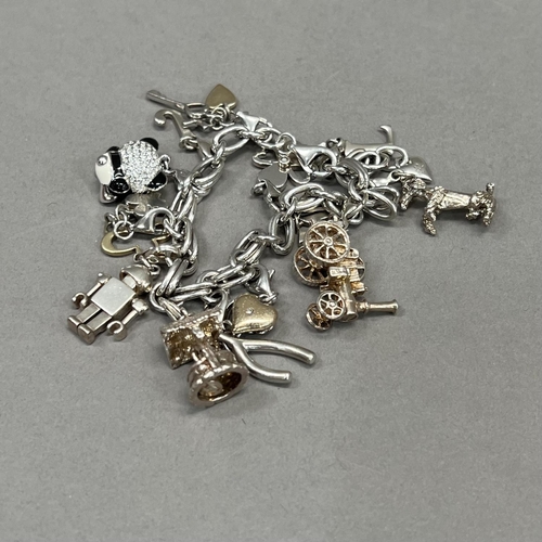 425 - A silver bracelet of trace and jump ring links hung with silver charms variously set with enamel, co... 