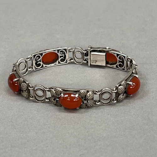 438 - A silver and cornelian bracelet, c1966, each foliate link of rectangular outline, claw set with an o... 