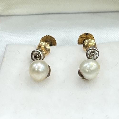 448 - A pair of cultured pearl and diamond earrings, c1920, in 9ct gold, each 5.5mm pearl pendant from a c... 