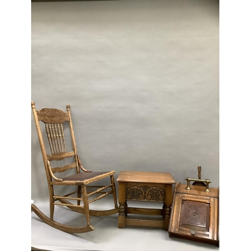 125 - An oak rocking chair with bobbin supports and carved crest together with an oak stool with carved fr... 