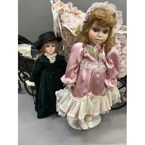 353 - Three modern dolls with porcelain heads and jointed bodies in a Victorian style pram with lace and a... 