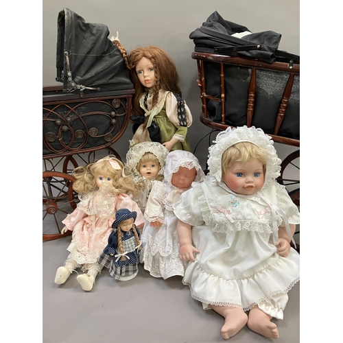 351 - A collection of six modern porcelain dolls in costume, together with two Victorian style prams