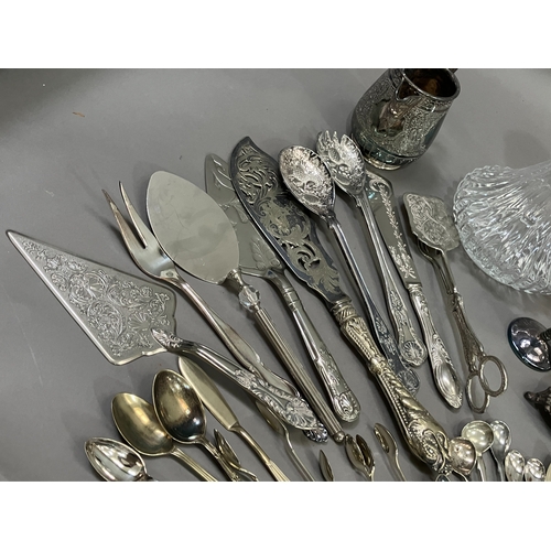 307 - A collection of silver plated ware and glass ware comprising two decanters with stoppers, salt and p... 