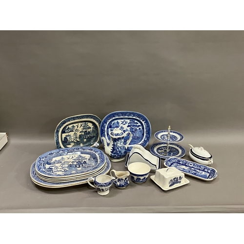 91 - A collection of blue and white ware comprising several willow pattern meat plates, willow pattern ca... 