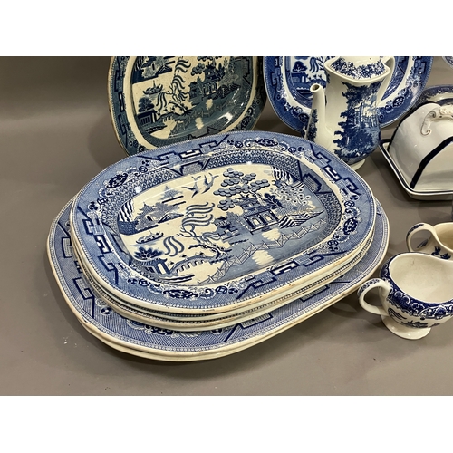 91 - A collection of blue and white ware comprising several willow pattern meat plates, willow pattern ca... 