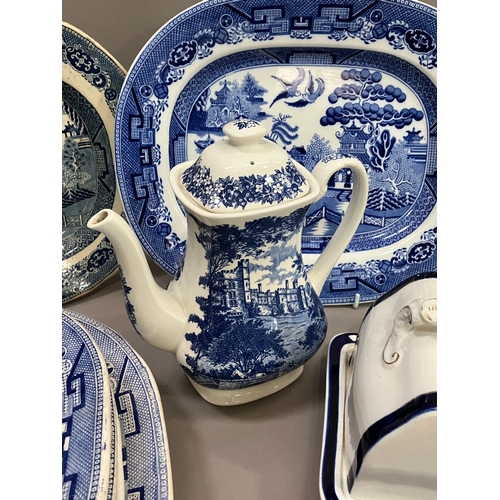 91 - A collection of blue and white ware comprising several willow pattern meat plates, willow pattern ca... 