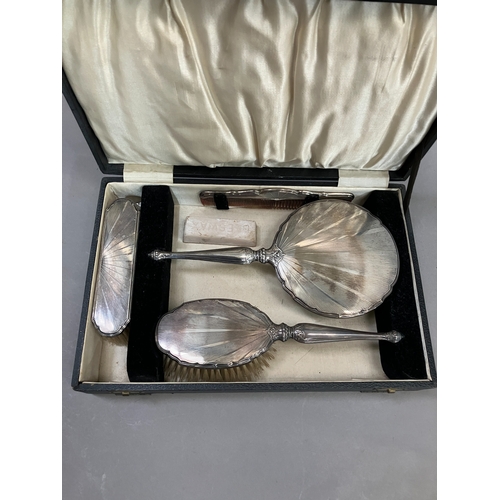 399 - Four piece silver backed dressing table set, Birmingham 1932 in fitted case, comprising hand mirror,... 