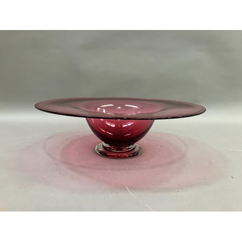 87 - A contemporary cranberry glass bowl with broad flat and folded rim on a clear glass foot, 38cm diame... 