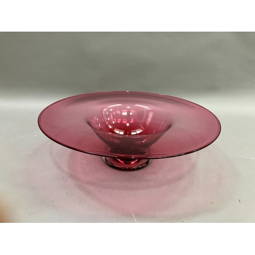 87 - A contemporary cranberry glass bowl with broad flat and folded rim on a clear glass foot, 38cm diame... 