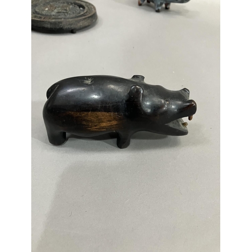 273 - A lignum vitae carving of a hippopotamus together with carved elephants in ebony and teak, a metal C... 