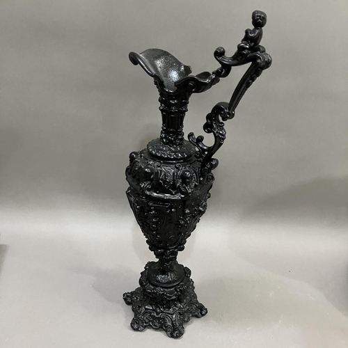 65 - A French black cast metal and heavily moulded ewer, the handle surmounted by cherub, 45cm high