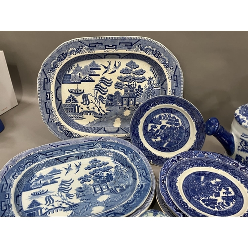 111 - A collection of blue and white ware including four willow pattern meat plates, side plates, dinner p... 