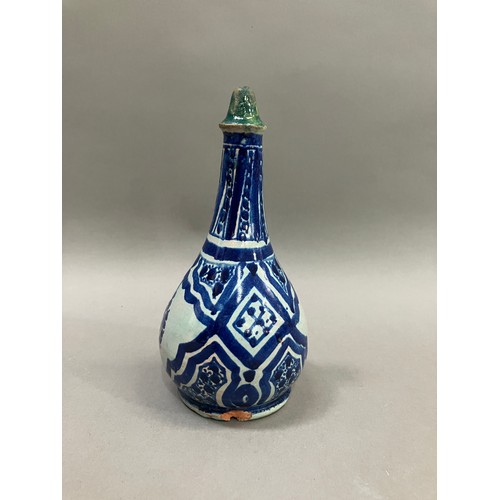 54 - A 19th century Middle Eastern earthenware bottle in grey white and painted in blue with lozenge pane... 