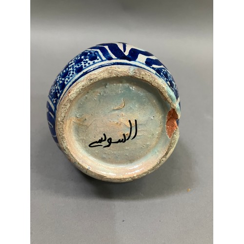 54 - A 19th century Middle Eastern earthenware bottle in grey white and painted in blue with lozenge pane... 