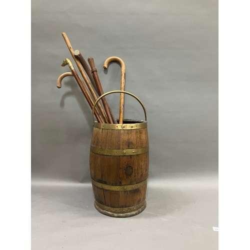 492 - A brass bound and oak coopered barrel stick stand with swing handle together with several walking st... 