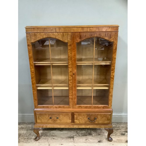 509 - A figured walnut bookcase having two arch profile doors glazed, the interior fitted with adjustable ... 