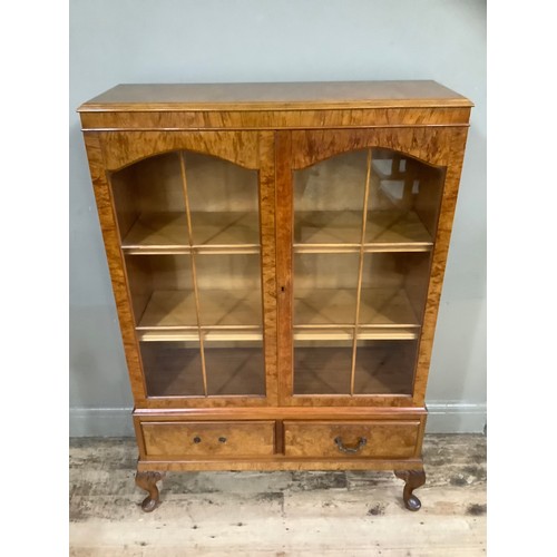 509 - A figured walnut bookcase having two arch profile doors glazed, the interior fitted with adjustable ... 