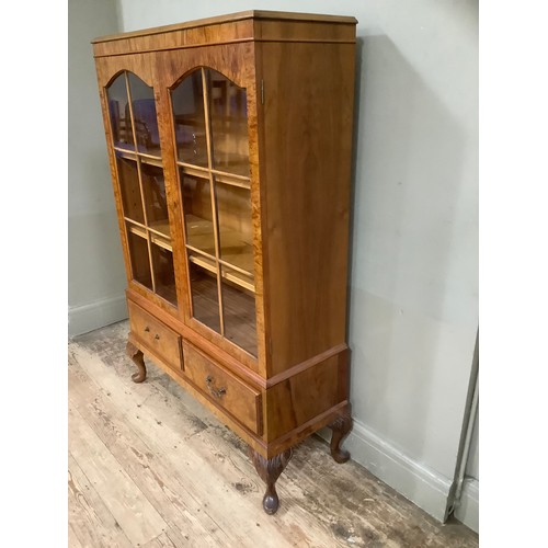 509 - A figured walnut bookcase having two arch profile doors glazed, the interior fitted with adjustable ... 