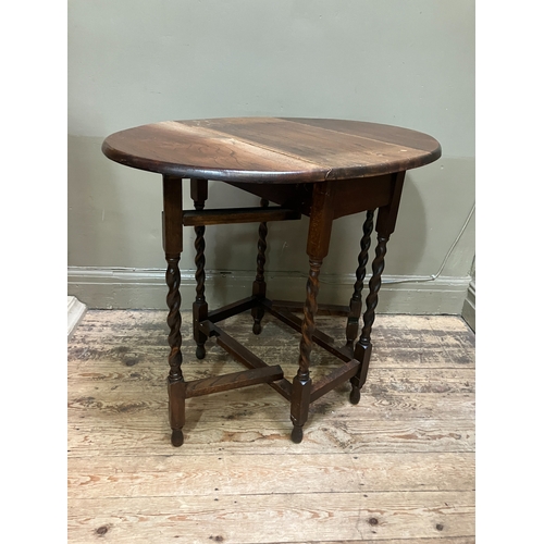 516 - A 1920/30s oak oval gate leg table having twin drop leaves and on slender barley twist supports and ... 