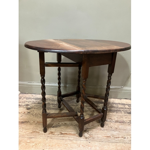 516 - A 1920/30s oak oval gate leg table having twin drop leaves and on slender barley twist supports and ... 