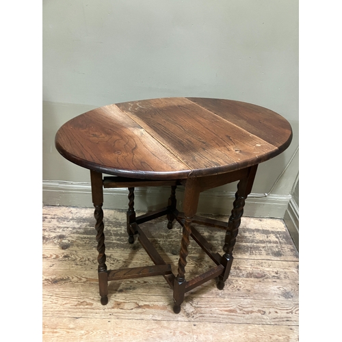 516 - A 1920/30s oak oval gate leg table having twin drop leaves and on slender barley twist supports and ... 