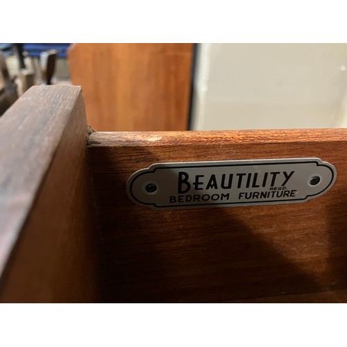 526 - A 1960s Beautility dark teak veneer chest of four heights with gilt metal handles and on ebonised ta... 