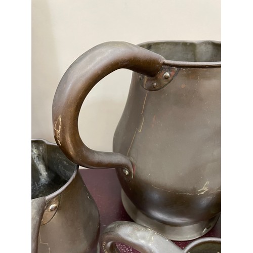 122 - A set of four copper jugs of graduated size measuring 28cm over handle, 22.5cm and 16cm