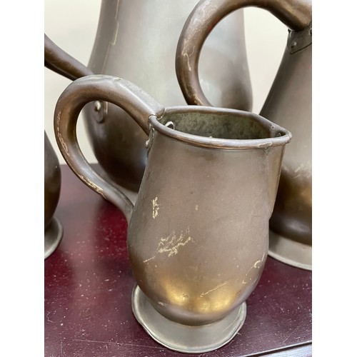 122 - A set of four copper jugs of graduated size measuring 28cm over handle, 22.5cm and 16cm