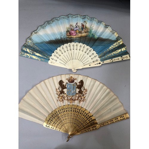 32 - Two mid-19th century fans, the first with carved and pierced wood sticks, painted in gold, the cream... 