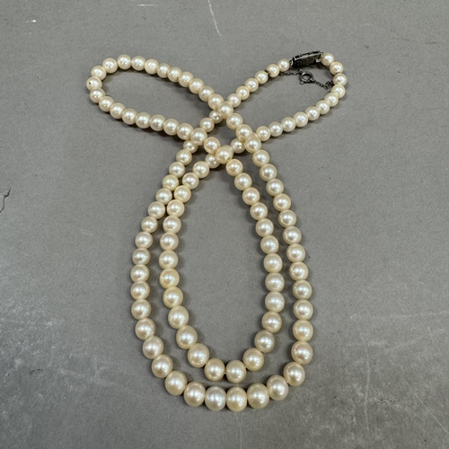 210 - A cultured pearl necklace, the approximate 6mm pearls fastened with a lozenge shaped engraved silver... 