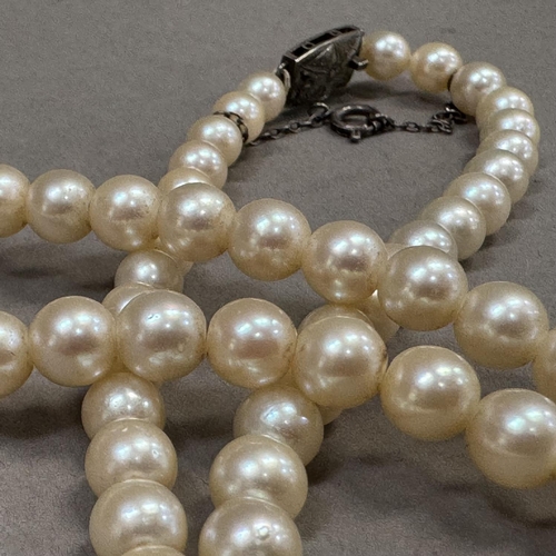 210 - A cultured pearl necklace, the approximate 6mm pearls fastened with a lozenge shaped engraved silver... 