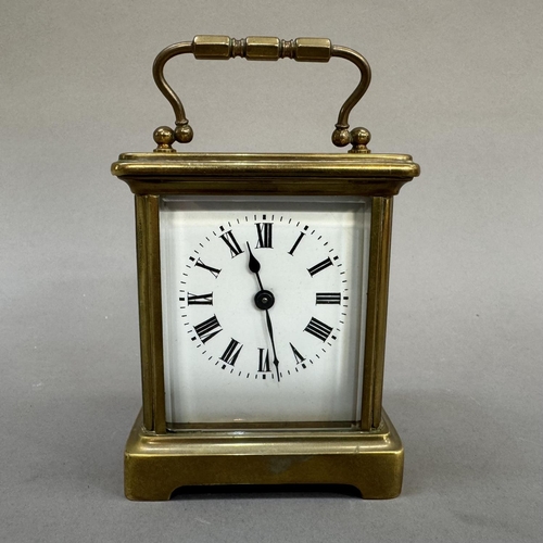 14 - An early 20th century brass carriage clock, enamel dial with black Roman numerals, 13cm over handle