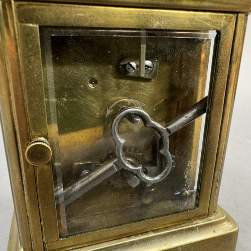 14 - An early 20th century brass carriage clock, enamel dial with black Roman numerals, 13cm over handle