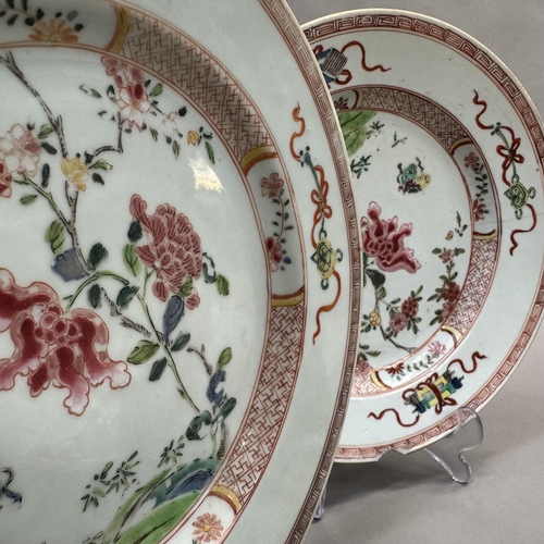 15 - A pair of early 20th century famille rose plates painted to the centre with rocks issuing peony and ... 