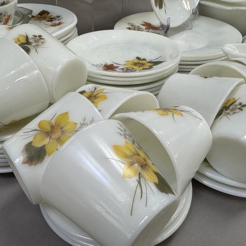 48 - An extensive collection of vintage Pyrex ware decorated with flowers in shades of brown and yellow, ... 