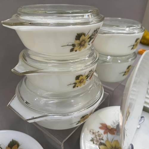 48 - An extensive collection of vintage Pyrex ware decorated with flowers in shades of brown and yellow, ... 