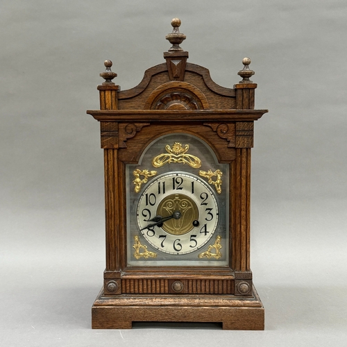 176 - A late 19th century oak mantel clock having a silver chaptering with black Roman numerals, applied g... 