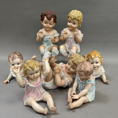 107 - A group of seven reproduction Bisque piano babies, 25cm to 16cm