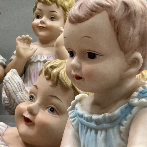 107 - A group of seven reproduction Bisque piano babies, 25cm to 16cm