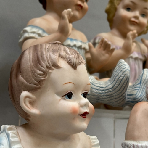 107 - A group of seven reproduction Bisque piano babies, 25cm to 16cm