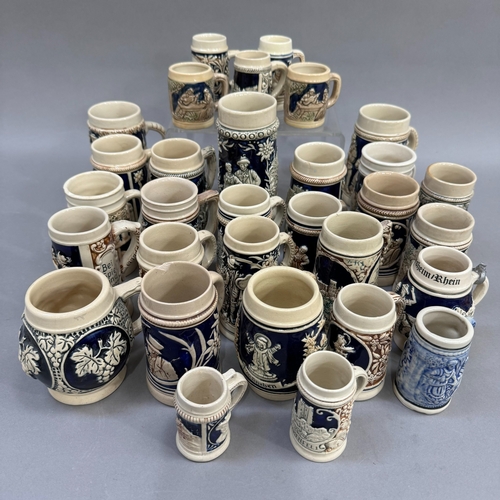 123 - A large quantity of German pottery steins glazed in blue and with relief moulded scenes