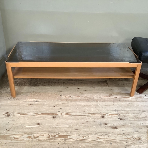 74 - A smoked glass and teak two tier coffee table 112cm x 48cm x 35cm together with a Stressless style b... 